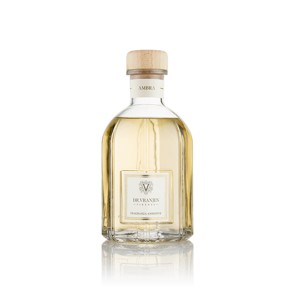 Eclectic Dr Vranjes Ambra reed diffuser in a clear glass bottle with a wooden cap against a black background.