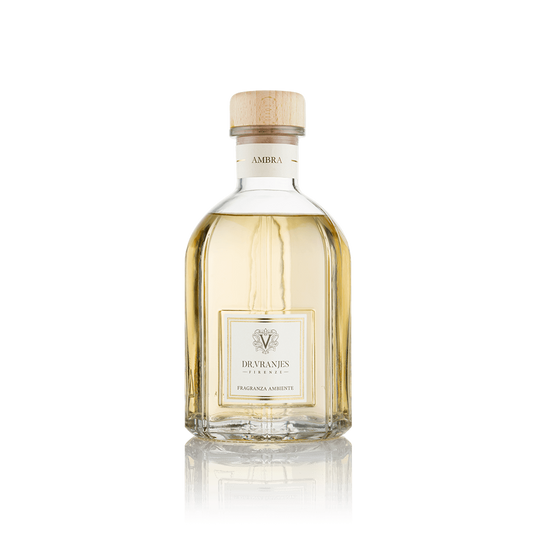 Eclectic Dr Vranjes Ambra reed diffuser in a clear glass bottle with a wooden cap against a black background.