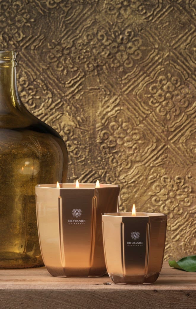 Eclectic Dr. Vranjes Oud Nobile scented candles in metallic gold glass vases on a wooden surface.