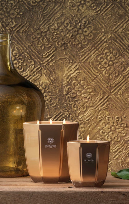 Eclectic Dr. Vranjes Oud Nobile scented candles in metallic gold glass vases on a wooden surface.