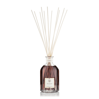 Eclectic Dr Vranjes Melograno reed diffuser in a glass bottle with natural sticks against a black background