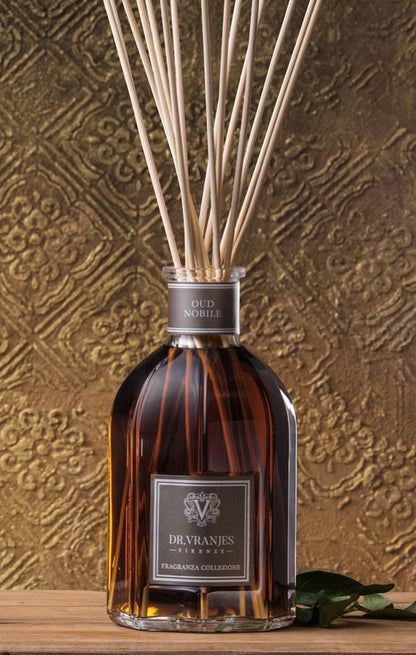 Eclectic Dr Vranjes Oud Nobile reed diffuser in a glass bottle with natural sticks against a textured gold background