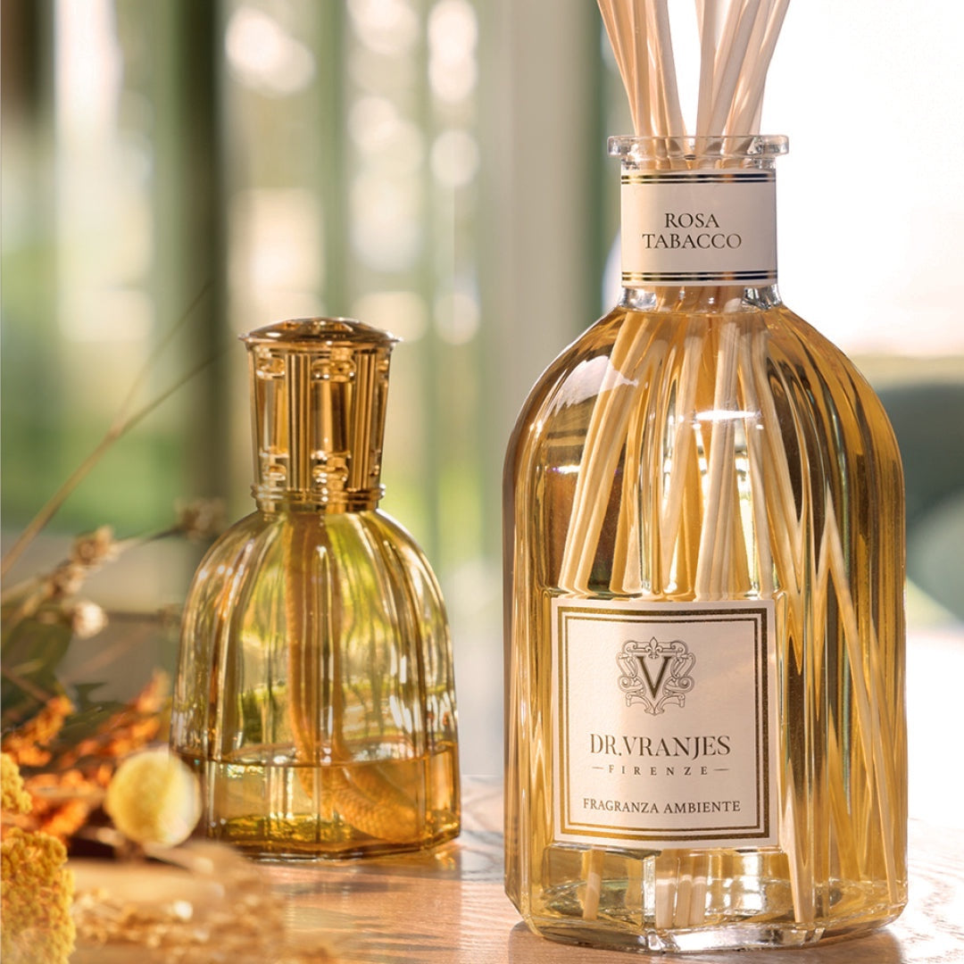 Eclectic Dr Vranjes Rosa Tabacco reed diffuser in a glass bottle with natural sticks on a wooden surface.