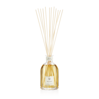 Eclectic Dr Vranjes Rosa Tabacco reed diffuser in a glass bottle with natural sticks against a black background.