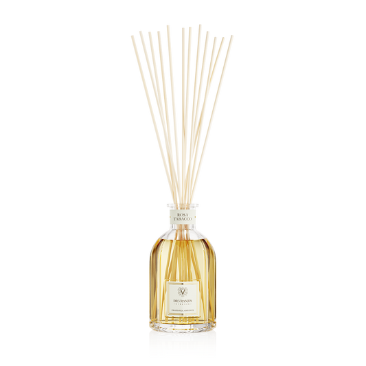 Eclectic Dr Vranjes Rosa Tabacco reed diffuser in a glass bottle with natural sticks against a black background.