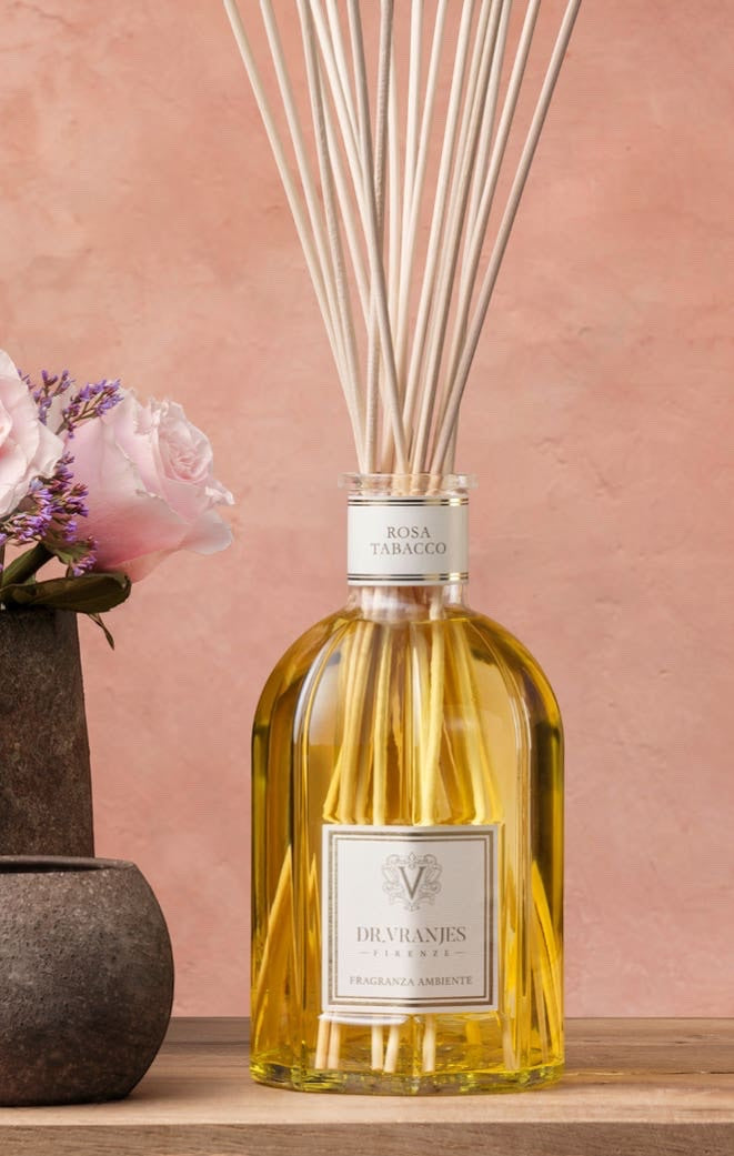Eclectic Dr Vranjes Rosa Tabacco reed diffuser in a glass bottle with natural sticks against a soft pink background.