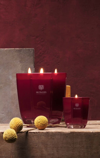 Eclectic Dr. Vranjes Rosso Nobile scented candles in tourmaline glass vases on a rustic wooden surface.