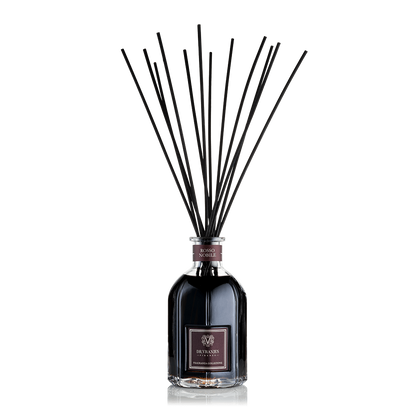 Eclectic Dr Vranjes Rosso Nobile reed diffuser in a glass bottle with black fragrance sticks against a black background.