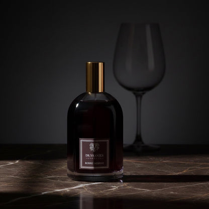 Eclectic Dr. Vranjes Rosso Nobile room spray in a glass bottle with a gold cap on a dark marble surface.