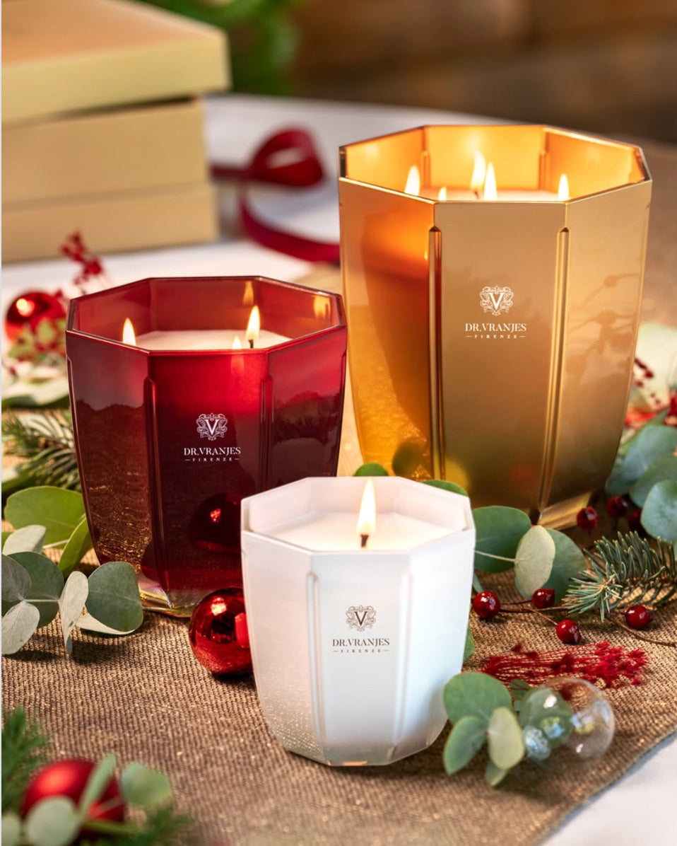 Eclectic Dr. Vranjes scented candles in pearl, red, and gold hexagonal glass vases with festive holiday decor.