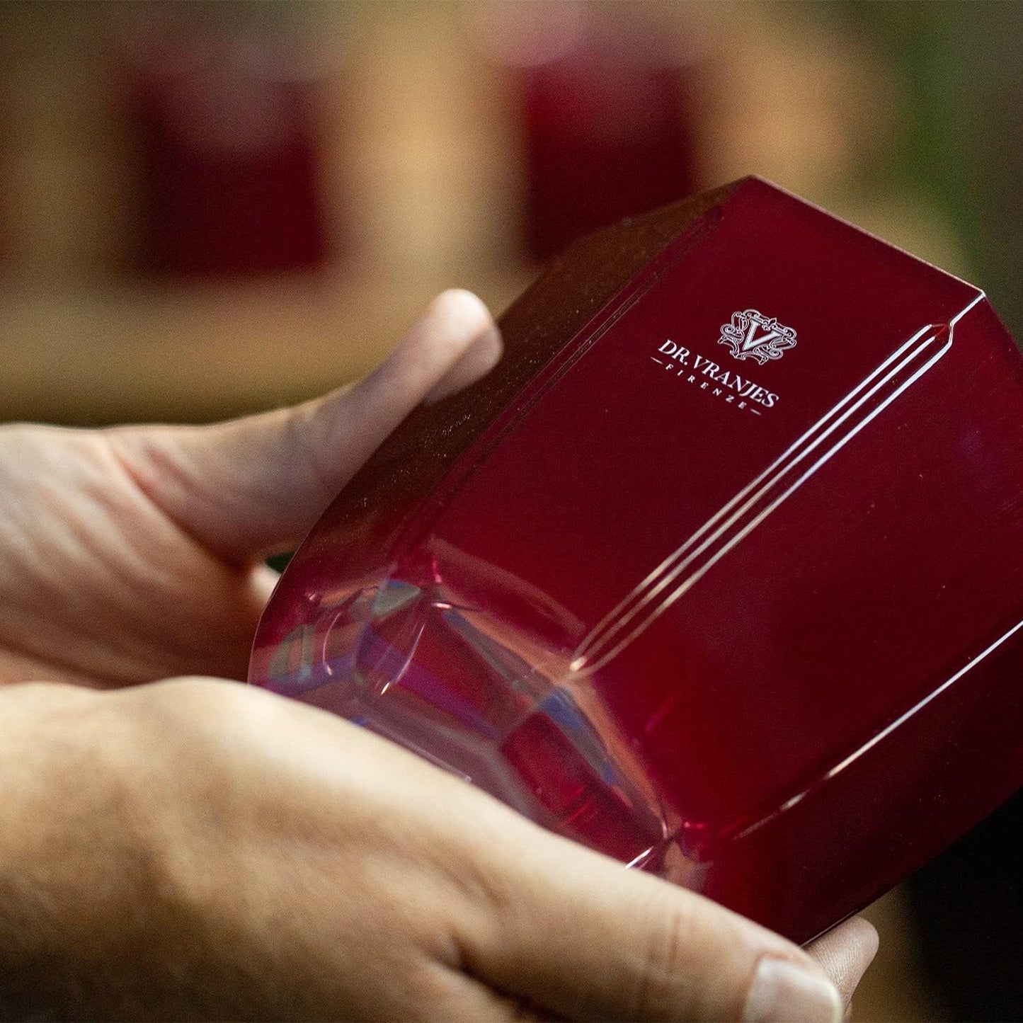 Eclectic Dr. Vranjes Rosso Nobile scented candle in a deep tourmaline-coloured glass vessel held in hands.