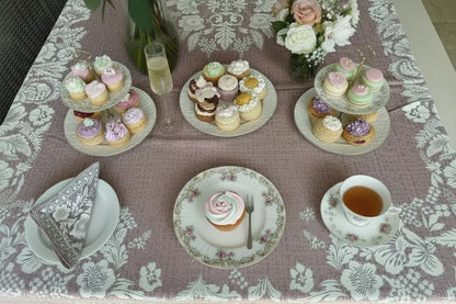 Eclectic floral linen-look tablecloth in dusty pink with a white damask pattern, set for a high tea dining experience.