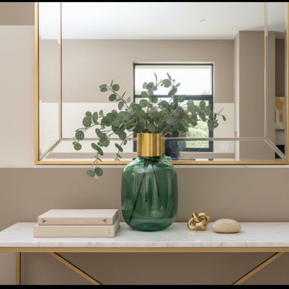 Eclectic emerald green textured glass vase with a brushed brass collar, styled with eucalyptus on a marble console table.