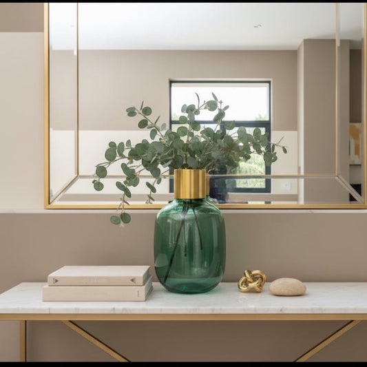 Eclectic emerald green textured glass vase with a brushed brass collar, styled with eucalyptus on a marble console table.