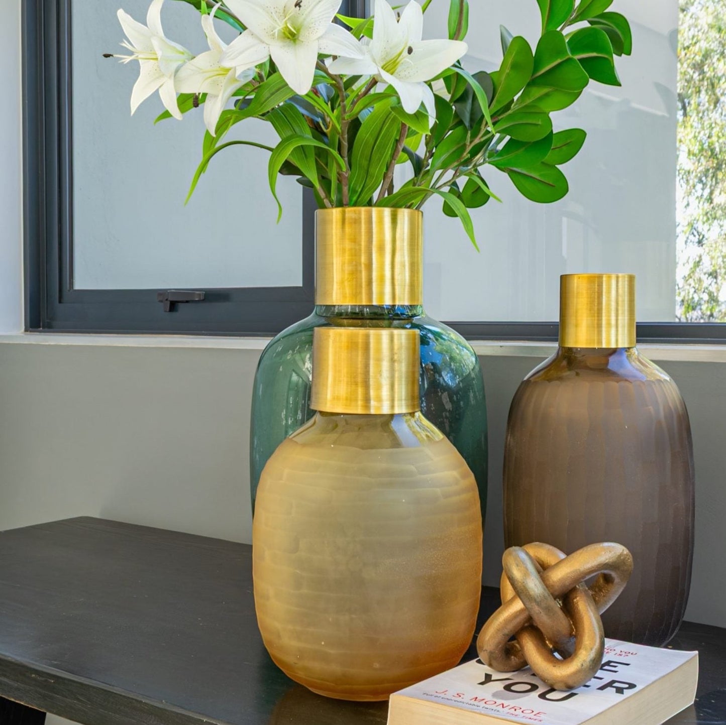 Eclectic emerald textured glass vase with brushed brass collar displayed on a dark console table with other decor