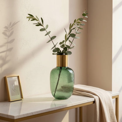 Eclectic emerald textured glass vase with a brushed brass collar holding eucalyptus stems on a marble console table.