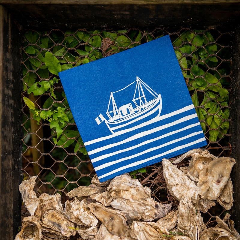 Eclectic Françoise Paviot Chalutier airlaid dinner napkin featuring a blue and white fishing boat print on oyster shells