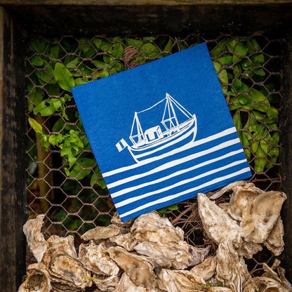 Eclectic Françoise Paviot Chalutier airlaid dinner napkin featuring a blue and white fishing boat print on oyster shells
