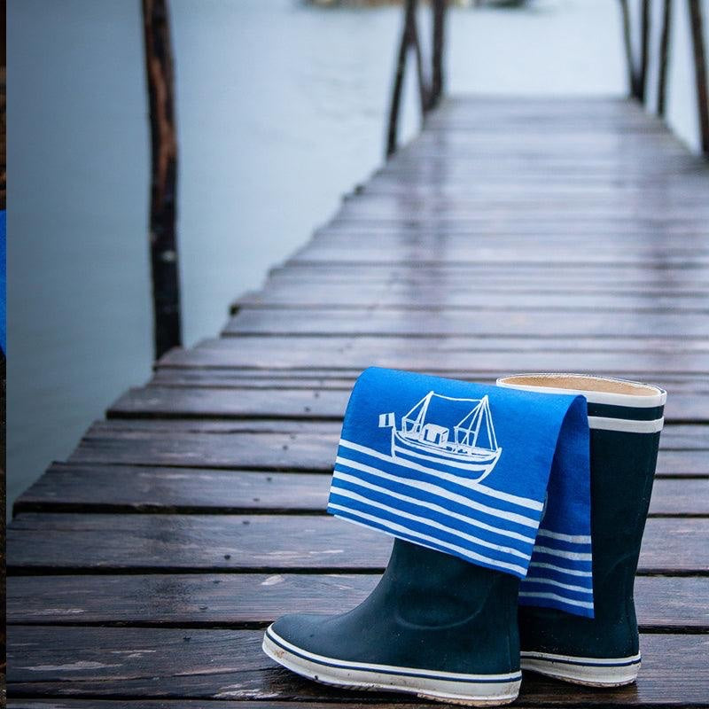 Eclectic Françoise Paviot Chalutier airlaid dinner napkin with blue and white fishing boat print on rubber boots