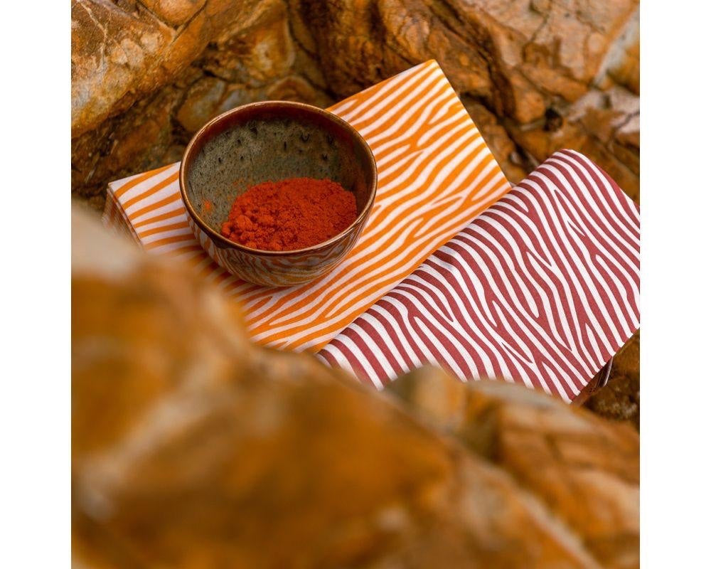 Eclectic Françoise Paviot Dune Terre airlaid dinner napkins with earthy striped patterns on a rocky surface.