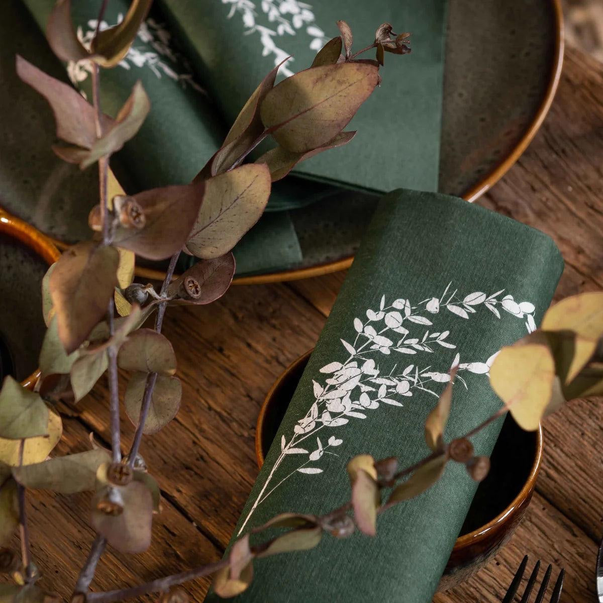 Eclectic Françoise Paviot deep green airlaid dinner napkins with white eucalyptus branch print on a wooden table