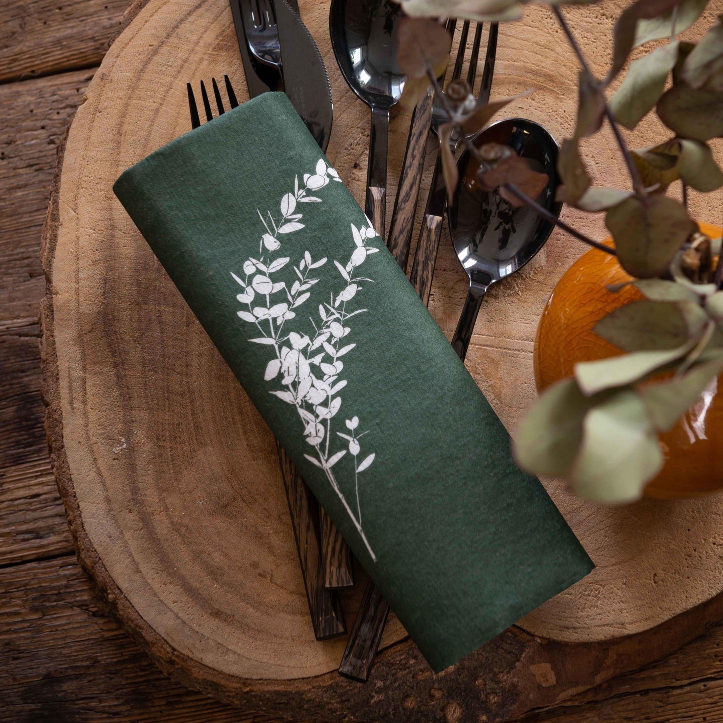 Eclectic Françoise Paviot deep green airlaid dinner napkin with white eucalyptus branch print on a wooden table