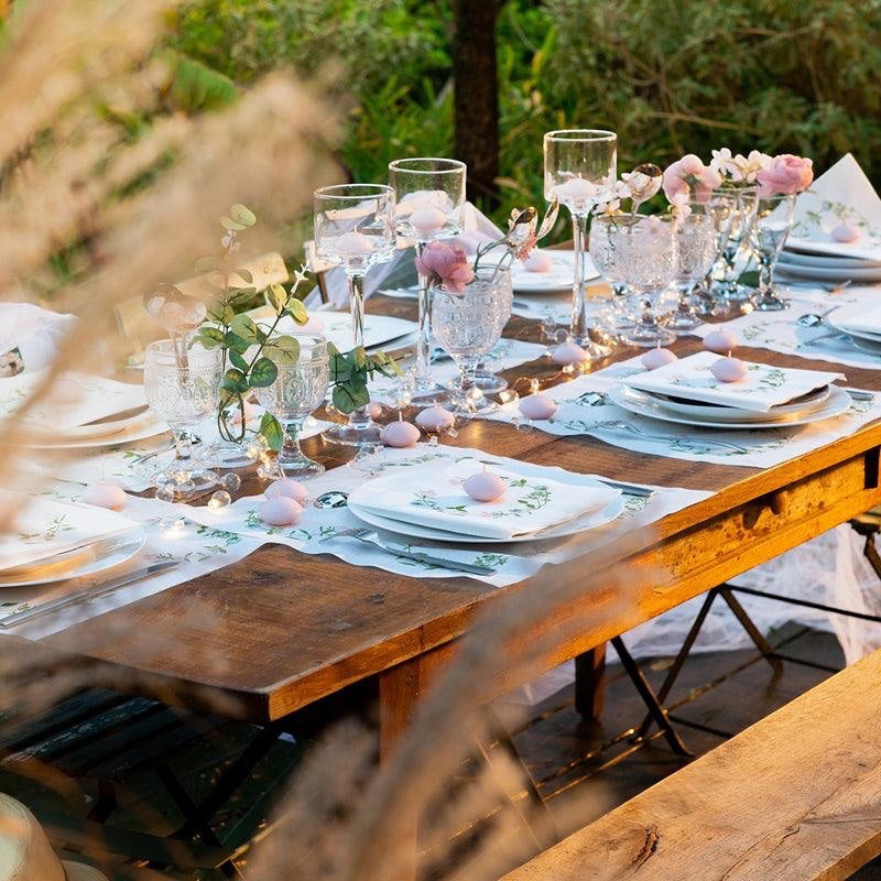 Eclectic Françoise Paviot Fleurs des Prés airlaid dinner napkins with wildflower wreath on a rustic outdoor table