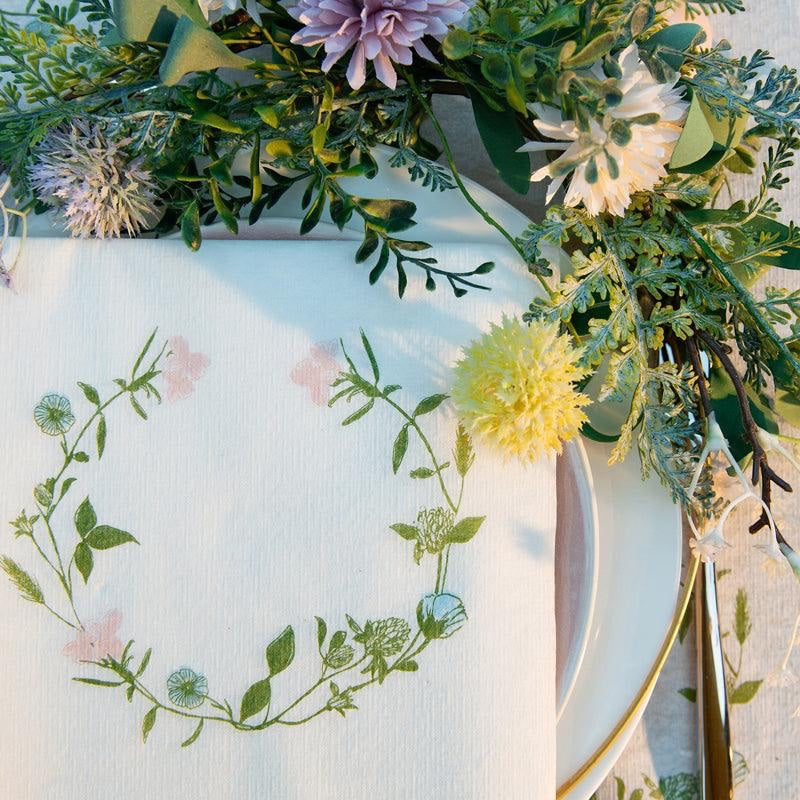 Eclectic Françoise Paviot Fleurs des Prés airlaid dinner napkin with a delicate pastel wildflower wreath design