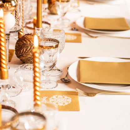 Eclectic Françoise Paviot gold airlaid dinner napkins styled on a formal dining table with candles and glassware