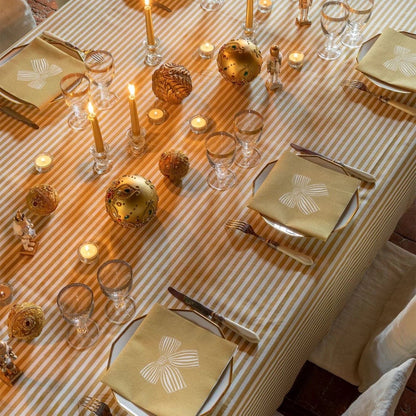 Eclectic Françoise Paviot Noeud Or gold dinner napkins with bow design on a festive striped table setting