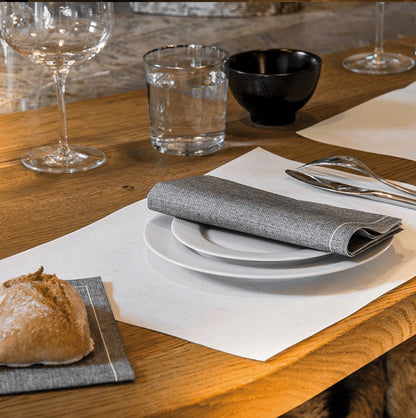 Eclectic Françoise Paviot grey textured airlaid dinner napkin folded on a white plate on a wooden table