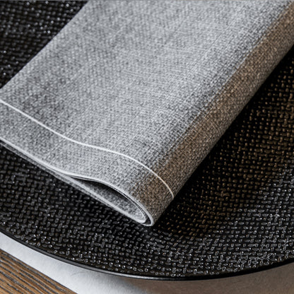 Eclectic Françoise Paviot Chine Gris grey airlaid dinner napkin with a textured linen-like finish on a black plate.