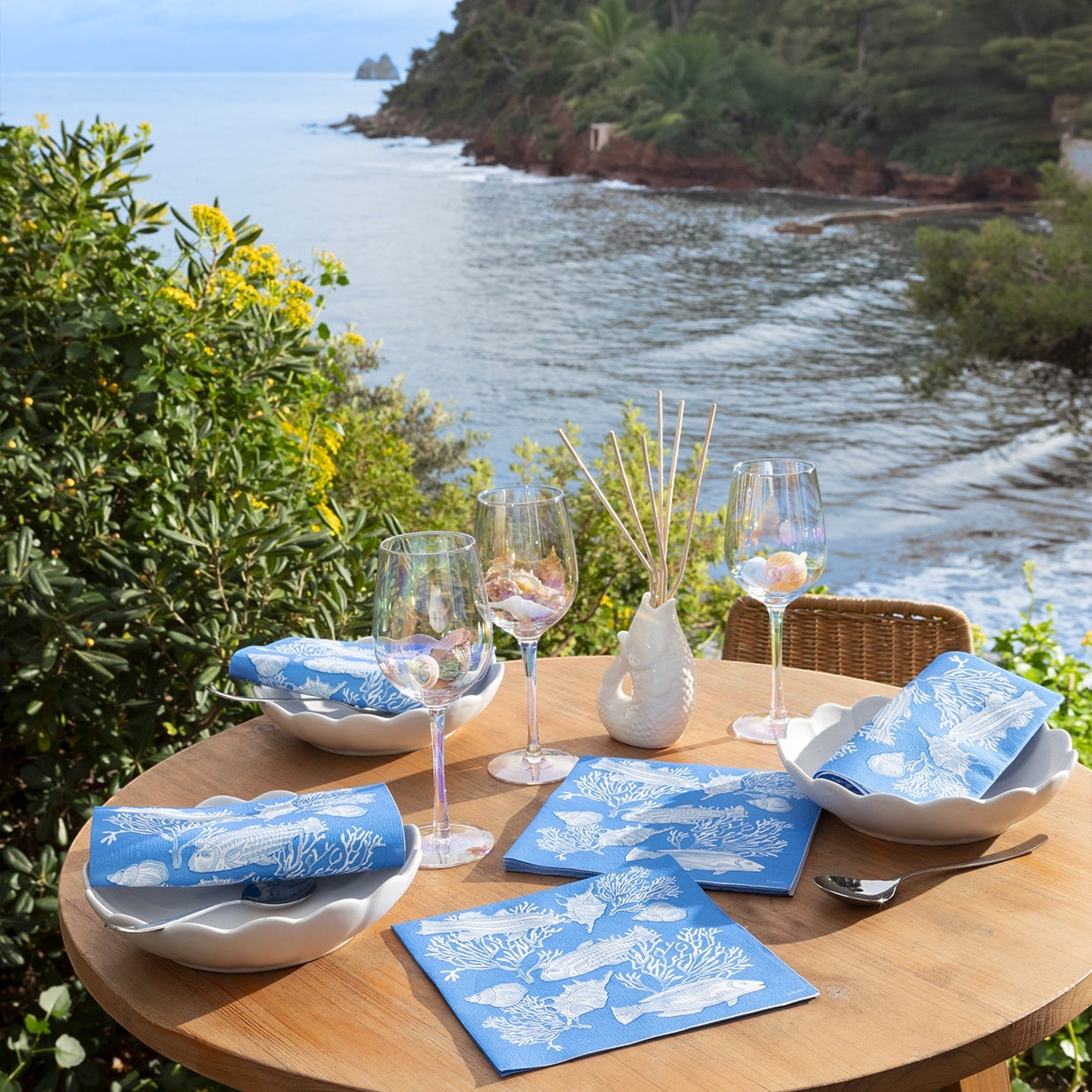 Eclectic Françoise Paviot Fonds Marin blue airlaid dinner napkins with fish and coral motifs on a coastal table setting.