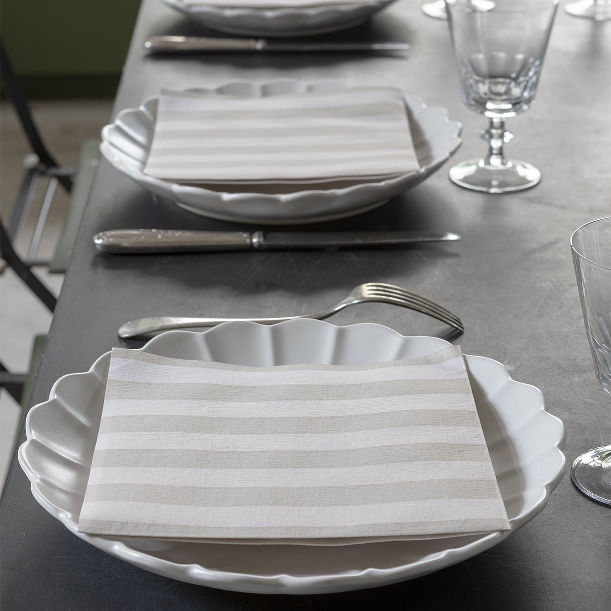 Eclectic Françoise Paviot Rayure Mocha striped airlaid dinner napkins on white scalloped plates at a table setting