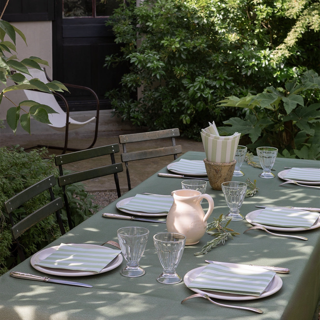Eclectic Françoise Paviot Rayure Olive striped airlaid dinner napkins set on an outdoor garden dining table