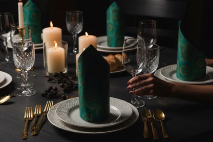 Eclectic Françoise Paviot Paon dinner napkins in emerald and teal with gold peacock feather patterns on a dining table