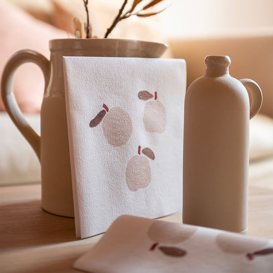 Eclectic Françoise Paviot Pomme airlaid dinner napkins with a minimalist apple motif in a neutral table setting.