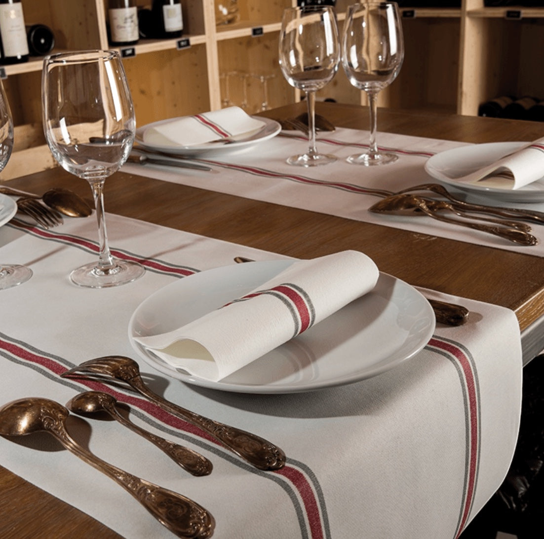 Eclectic Françoise Paviot Torchon Rouge airlaid dinner napkins with red and grey stripes on a rustic wooden table
