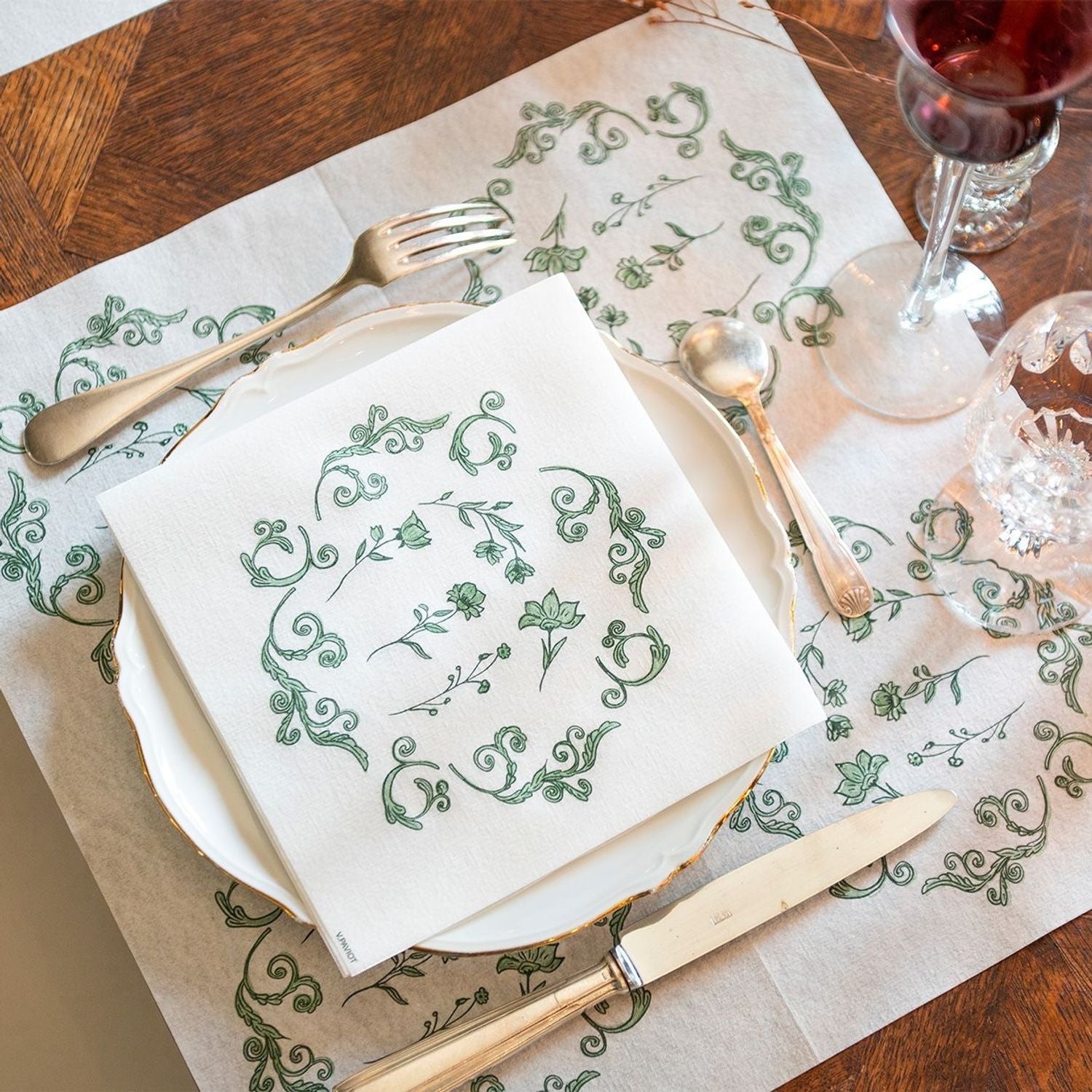 Eclectic Françoise Paviot Régence Vert airlaid dinner napkin with green botanical motifs on a white place setting