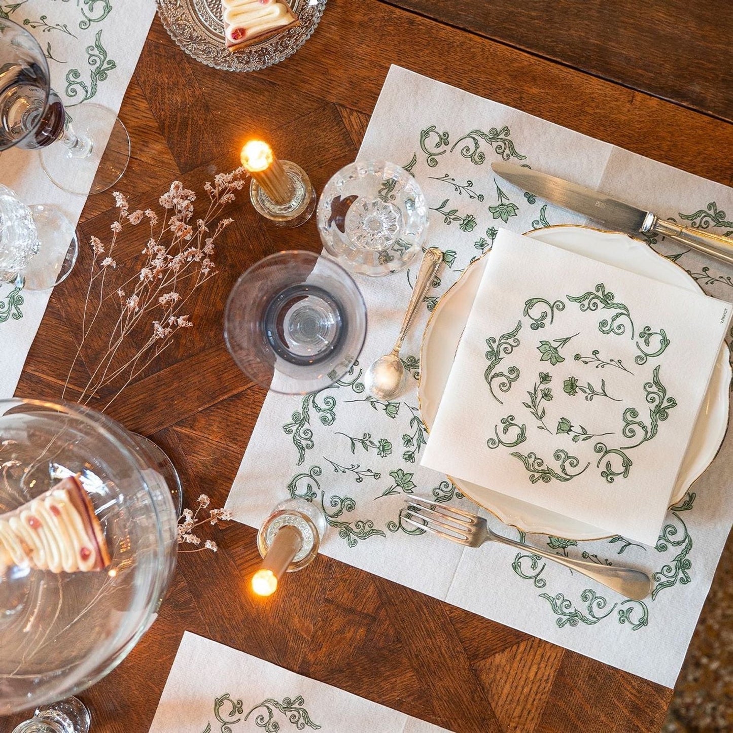 Eclectic Françoise Paviot Régence Vert airlaid dinner napkins with green botanical motifs on a wooden dining table.