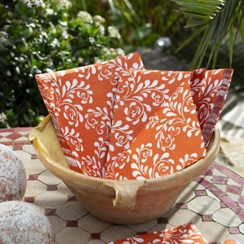 Eclectic Françoise Paviot Arabesque Terra dinner napkins with white floral patterns in a rustic bowl on a tiled table.