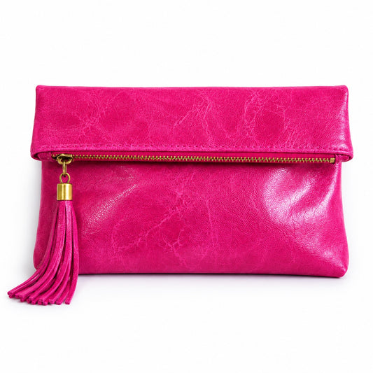 Eclectic fuchsia leather foldover clutch with a decorative tassel and zip closure on a white background.