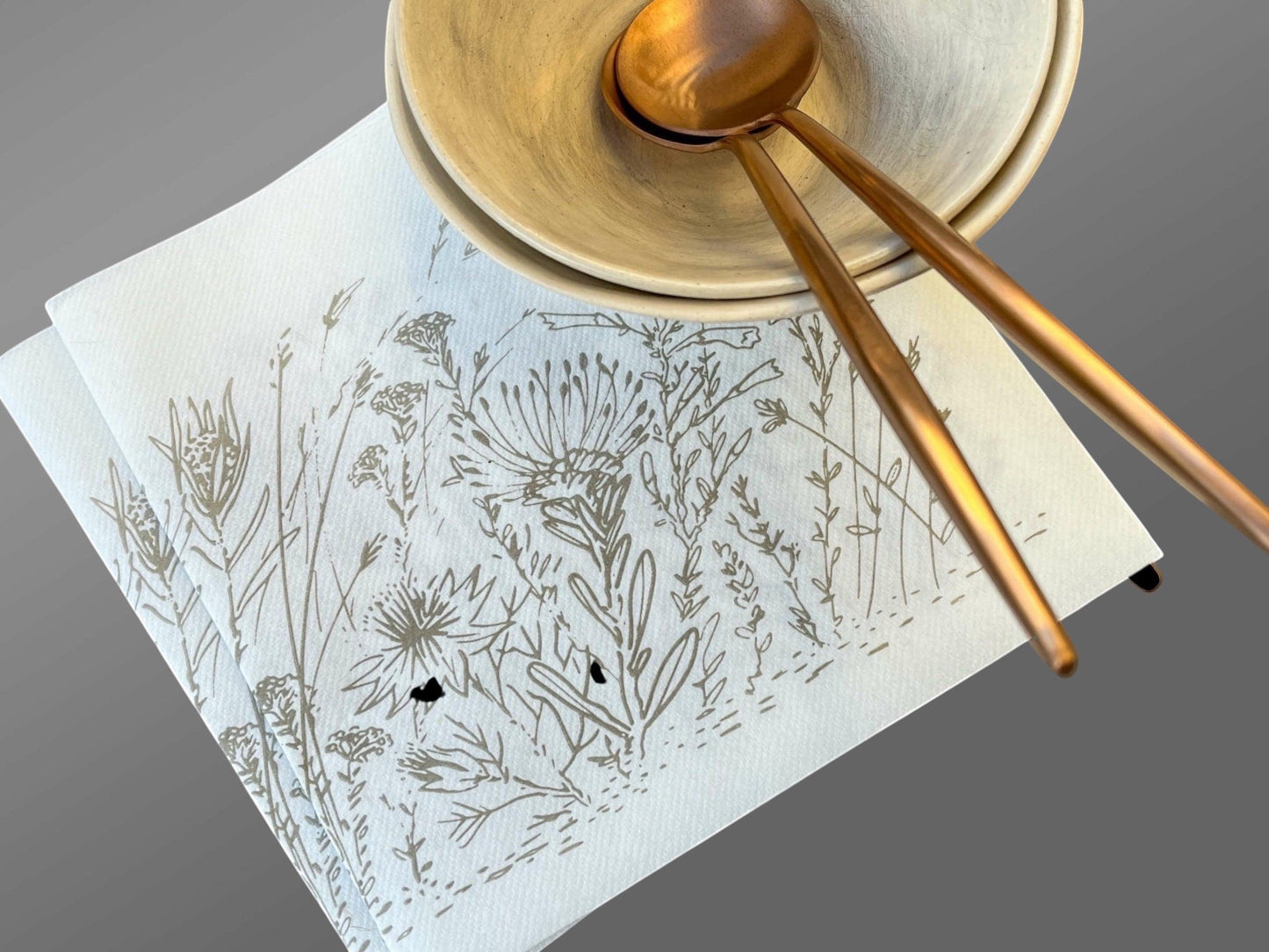 Eclectic Fynbos oatmeal botanical print airlaid napkins with linen-like texture, styled with ceramic bowls and spoons.