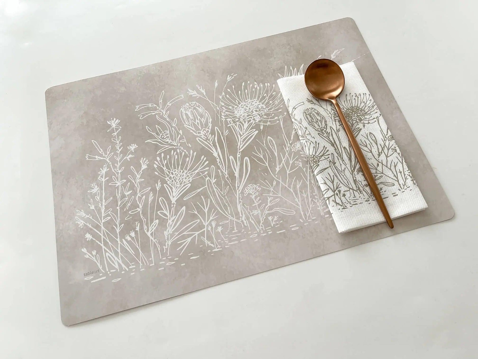 Eclectic Fynbos Oatmeal reusable paperboard placemat with white botanical linework and a matching napkin with spoon.