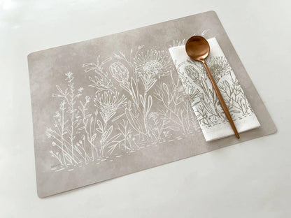 Eclectic Fynbos Oatmeal reusable paperboard placemat with white botanical linework and a matching napkin with spoon.