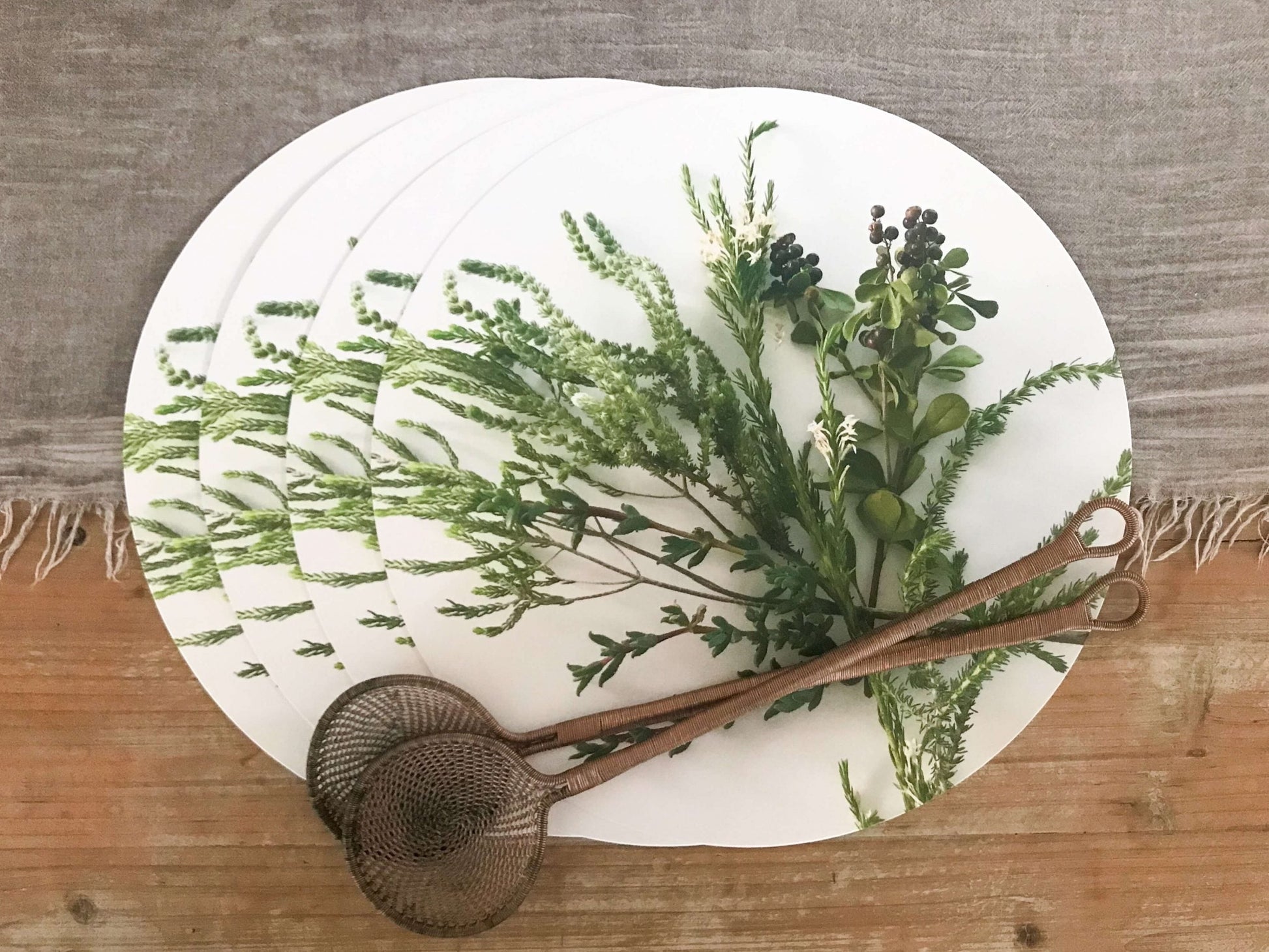 Eclectic set of four round white paperboard placemats with green botanical fynbos illustrations and a satin finish.