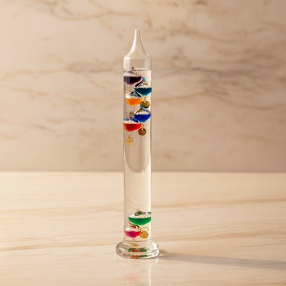 Eclectic 30cm Galileo glass thermometer with seven floating multi-coloured spheres on a marble surface.