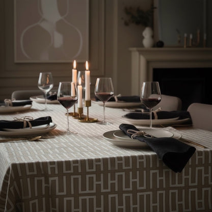 Eclectic natural linen-look tablecloth with a geometric pattern on a dining table set with black napkins and wine.
