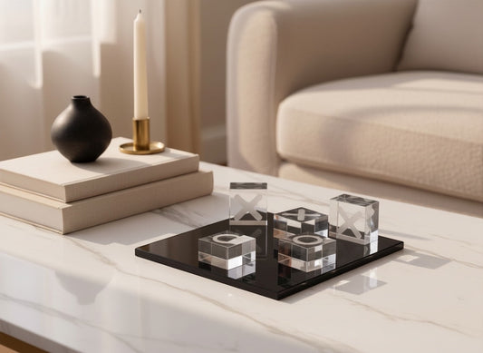 Eclectic glass noughts and crosses game with clear glass pieces on a sleek black base displayed on a marble table.