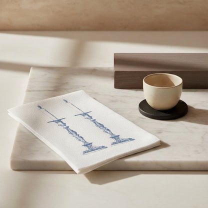 Eclectic Good Shabbas slimline disposable paper napkin with blue candle holder print on a white marble surface